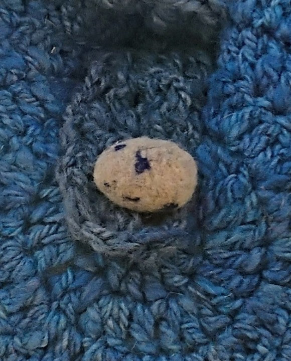 Close-up of needle felted spotted blue egg button closure on handspun wool chicken bag