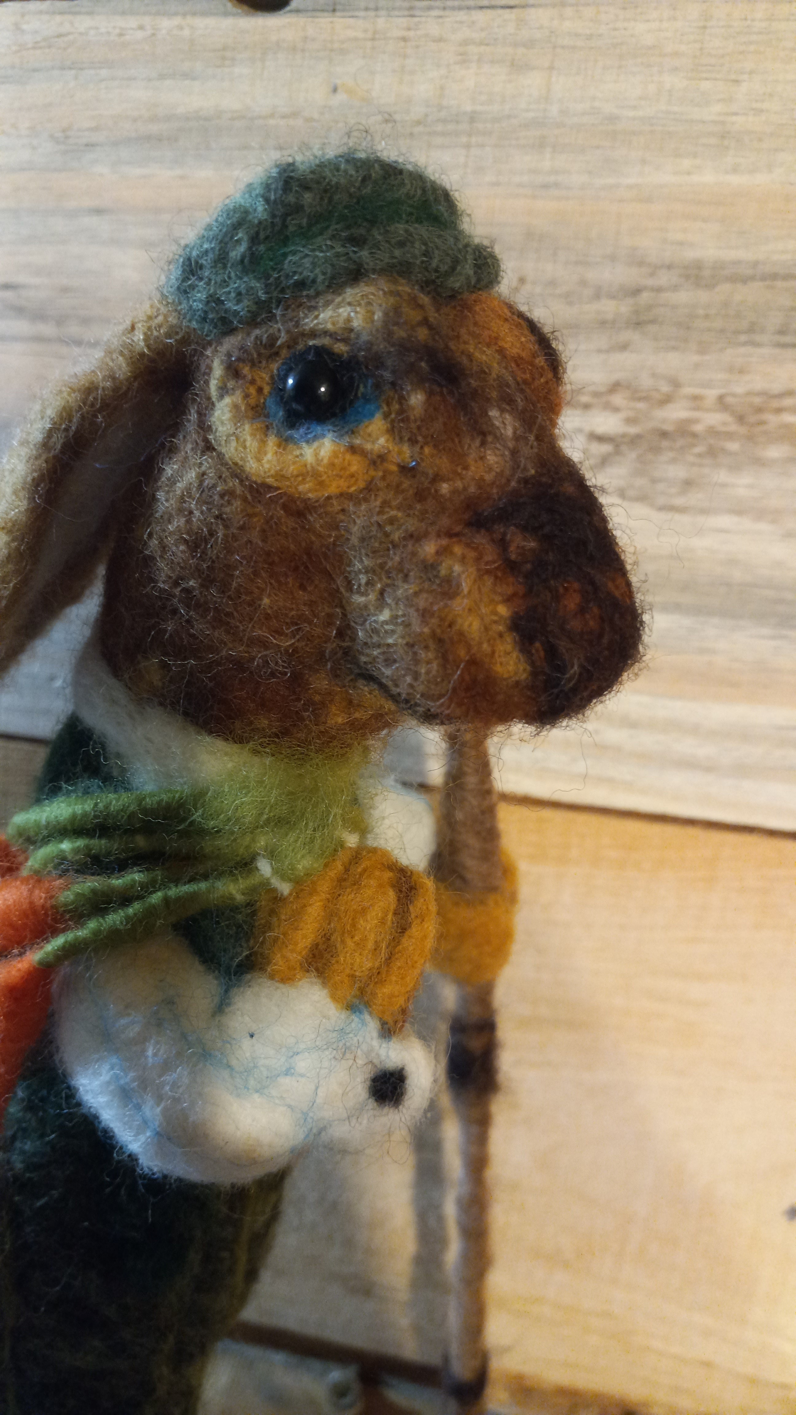 Close-up of The Carrot Hunter rabbit face showing glass eyes and teal flat cap